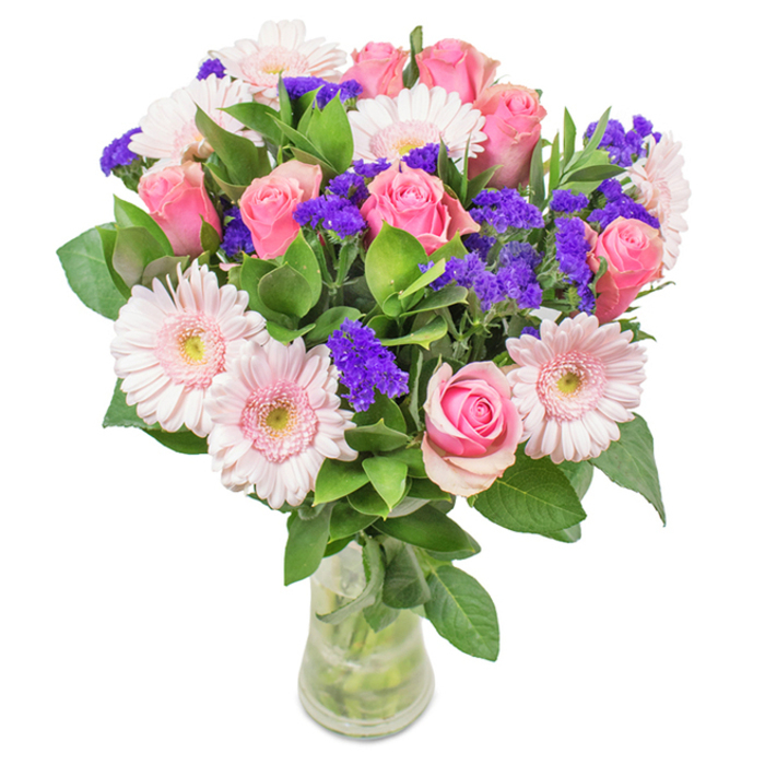 This radiant floral composition, expertly assembled in Radlett, features a balanced blend of soft to medium pink roses-about seven to nine in number-each one either tightly furled or blossoming into a classic spiral, hinting at skillful, gentle handling. Intertwined amongst them are five to seven pale pink Gerbera daisies, their large round faces and light petal tones exuding gentle optimism. Clusters of vivid purple statice or limonium thread through the arrangement, introducing welcome contrast and a lively texture. Lush, deep green foliage serves as a cumulative, verdant backdrop, echoing the abundant natural beauty of Radlett's Woodfield Park. The entire bouquet is showcased in a pristine glass vase, stems and crystal-clean water visible, reinforcing a sense of freshness and care. This beautiful gift, available for same-day delivery in Radlett, is ideal for occasions ranging from birthdays and anniversaries to an elegant touch for home or office, encapsulating joy, affection, and the special charm of Radlett's floral artistry.